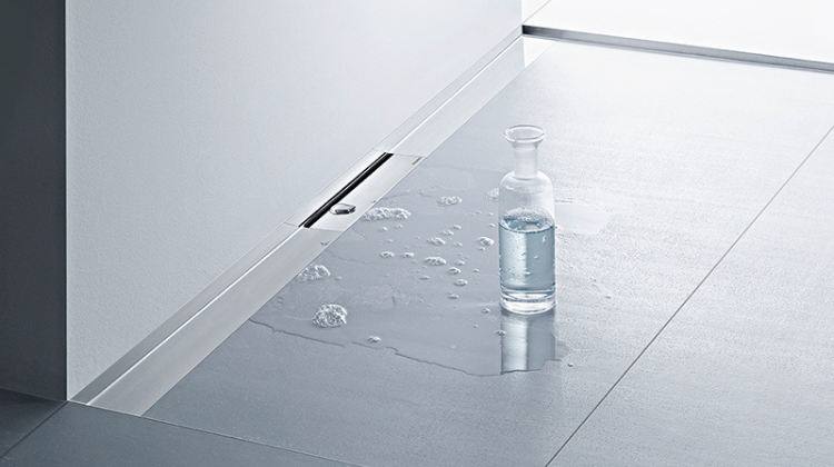 Bodengleiche Dusche mit Glasflasche und Wasser auf Fliesenbo