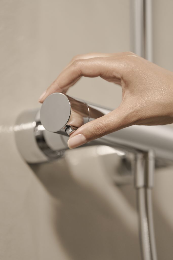 Hand greift verchromten Wasserhahn mit runder Form