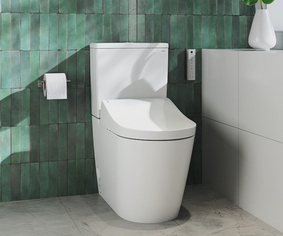 Stand-Dusch-WC vor grünem Fliesenspiegel.