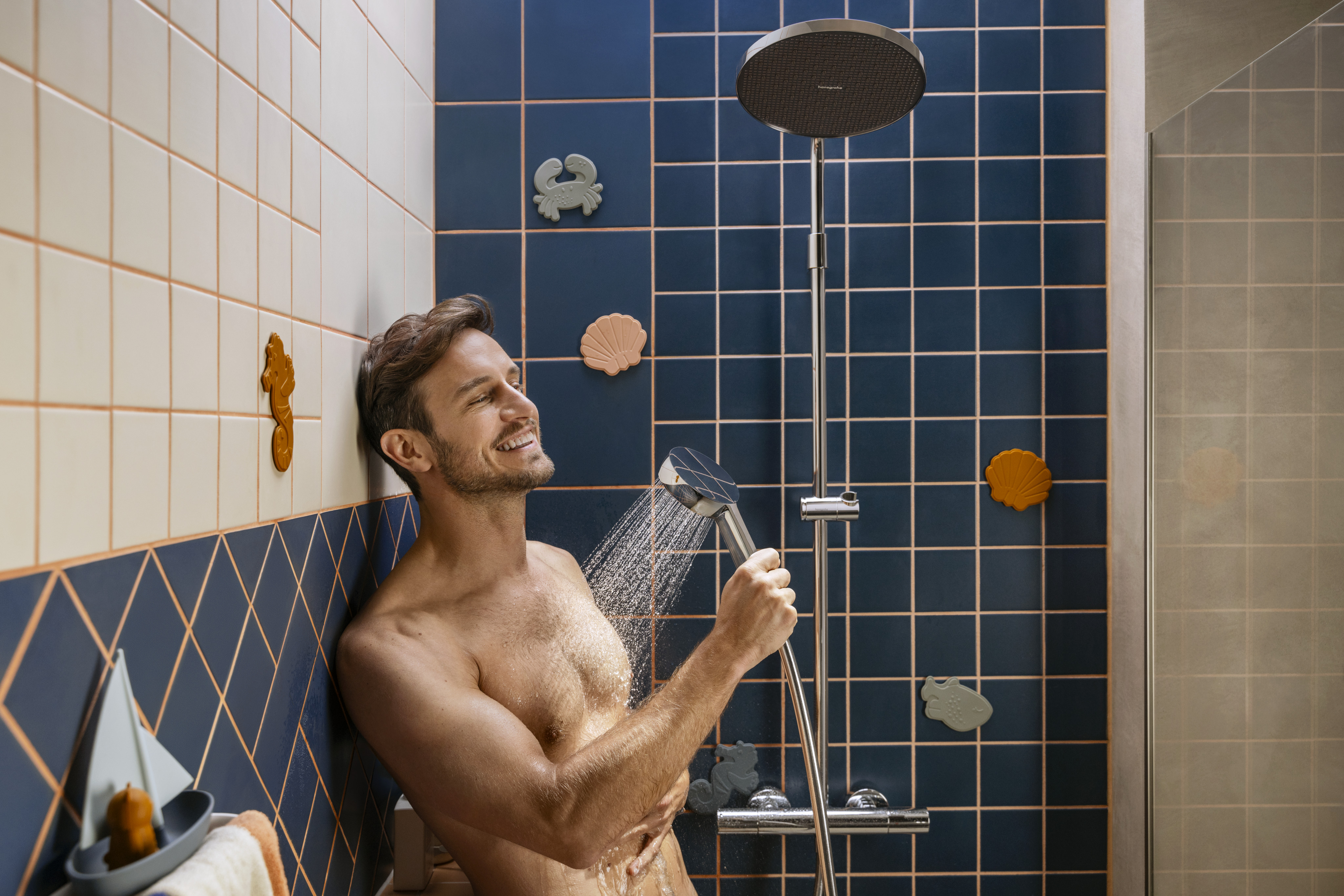 Mann duscht glücklich mit Handbrause vor blauen und weißen F