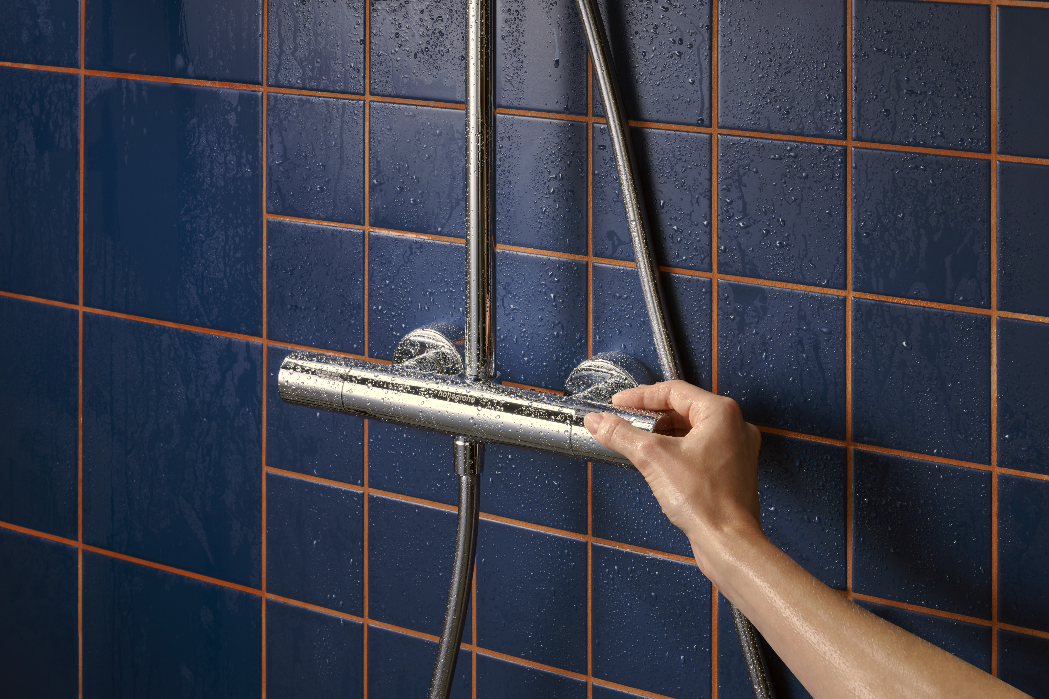 Hand stellt Thermostat Duscharmatur an nassen blauen Fliesen